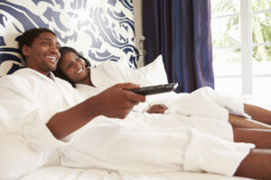 Couple Relaxing In Hotel Room Watching Television